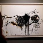 A woman looks at a painting of an man lying down.