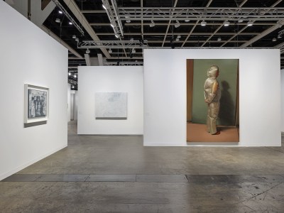 View of an art fair booth with three paintings on three different walls.