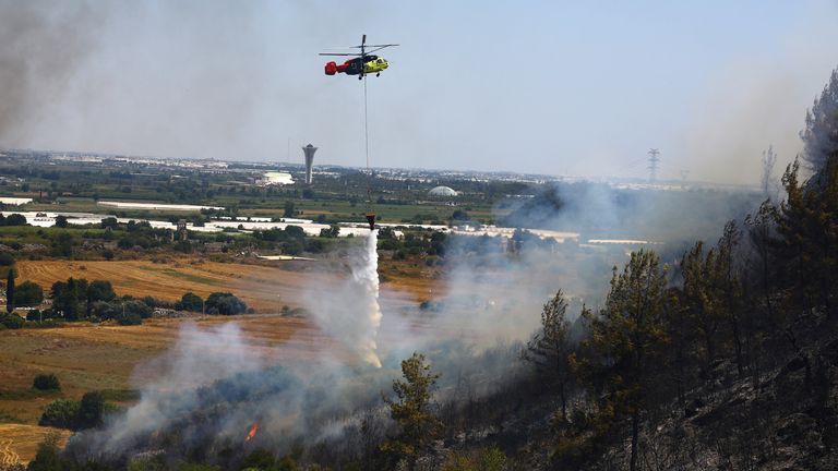 A firefighting helicopter drops water to extinguish a wildfire in the Aksu district of Antalya.
Pic: Reuters