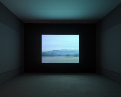 A video in a darkened room showing an island and a shore with lines running across it.