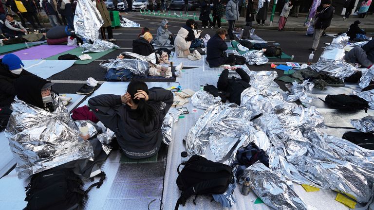 Demonstrators who stayed overnight near the constitutional court wait for the start of a rally calling for the president to step down. Pic: AP