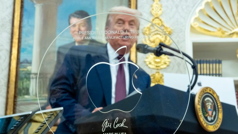Trump seen through the trophy given to him by Tim Cook. Pic: AP