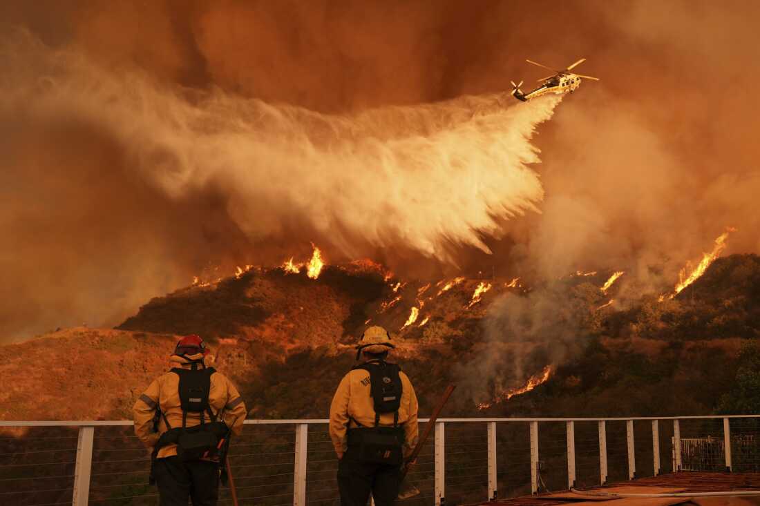 Firefighters watch a helicopter drop water on the Palisades Fire in Mandeville Canyon in Los Angeles in January 2025. California sued oil and gas companies in 2023 for allegedly misleading the public about the dangers of fossil fuels, which are the primary cause of climate change. The fossil fuel industry says lawsuits like California's are meritless and politicized.
