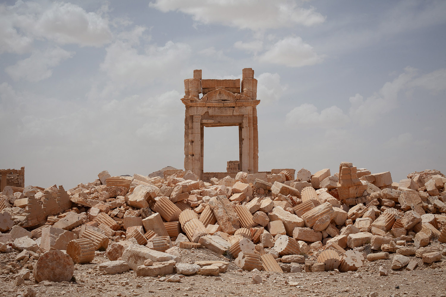 An archway atop a pile of rubble and broken columns.