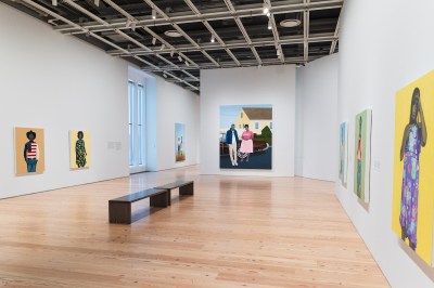A museum gallery hung with portraits of Black men and women painting against monochromatic pastel backgrounds.