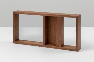 A sculpture of wood that is bisected. One half is fully inset with glass. The other half is half wood and half glass.