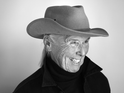 A black and white portrait of a white woman in a cowboy hat smiling.