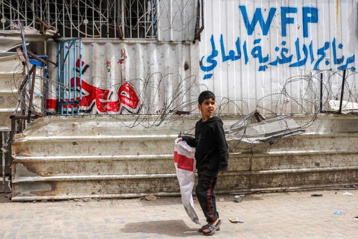 A Palestinian boy carrying an empty flour sack walks past a shuttered World Food Program bakery in Gaza City that ran out of supplies, on April 1, 2025. The UN agency announced it will close the remainder of its bakers in the territory as food continues to dwindle as a result of Israel's continued aid blockade.