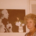 A woman standing beside a large picture of a mummy on a wall.