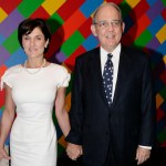 A man in a suit and a woman in a dress before a large abstract painting.