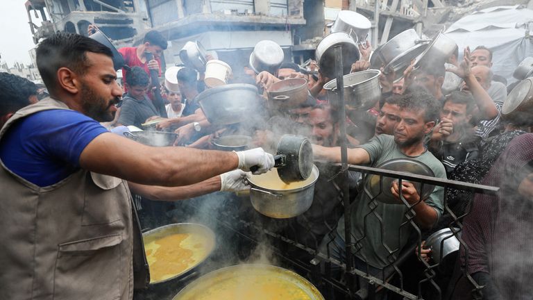 Palestinians receive food cooked by a charity kitchen in Beit Lahia, northern Gaza. Pic: Reuters