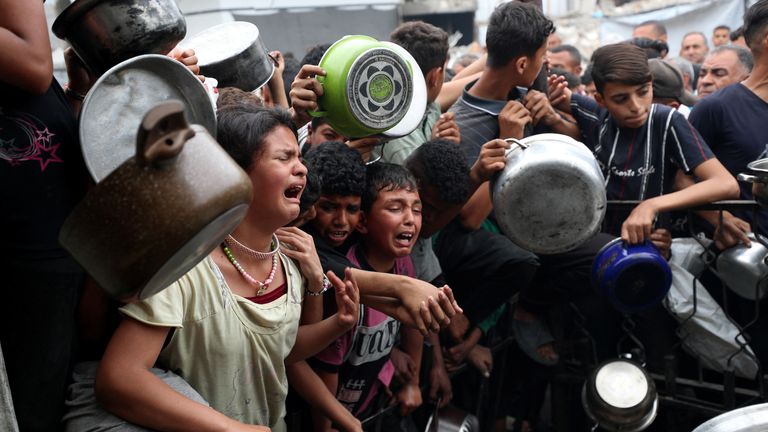 Children wait to receive food cooked by a charity kitchen in Beit Lahia, northern Gaza. Pic: Reuters