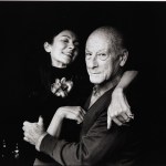 A man and a woman hug while smiling at the camera.