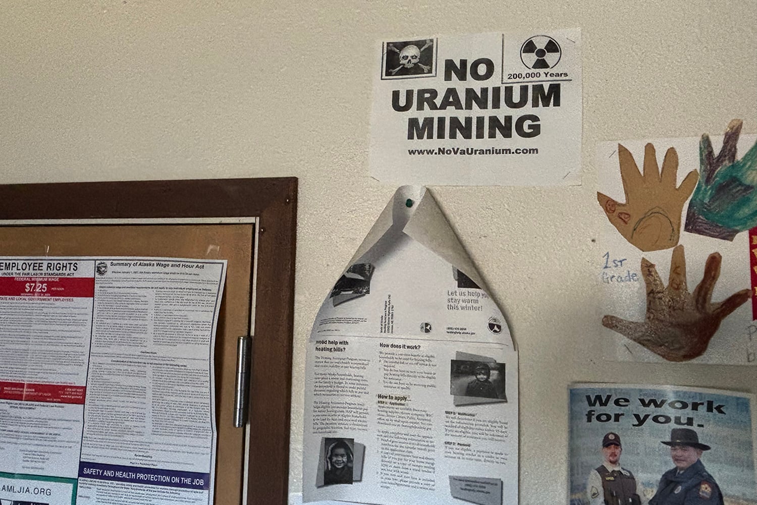 Signs on a wall including one with a skull and cross bones and nuclear sign that says "NO URANIUM MINING."