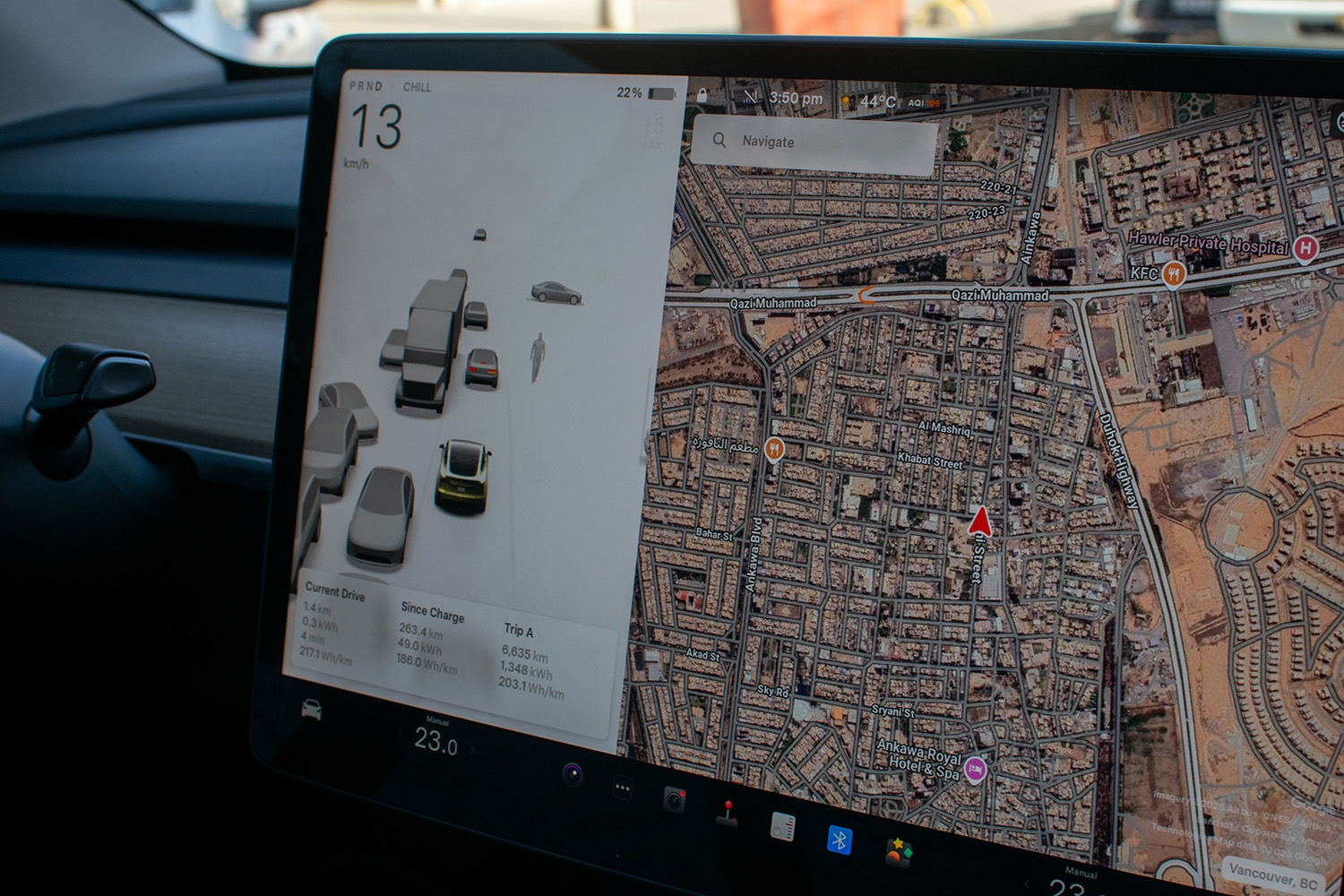 A large screen inside a Tesla car shows a street view of Erbil.