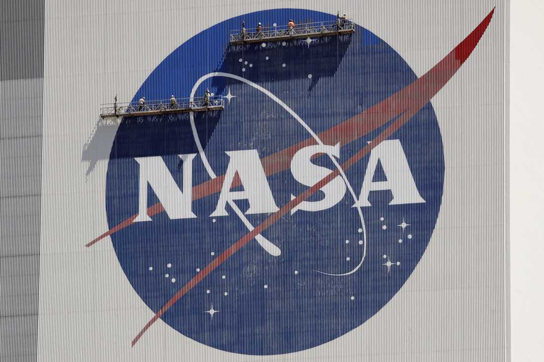 Workers on scaffolding repaint the NASA logo near the top of the Vehicle Assembly Building at the Kennedy Space Center in Cape Canaveral, Fla., May 2020.