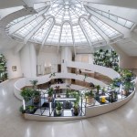 A ramp surrounding an inner atrium whose inner walls have grid-like structures with plants in them.