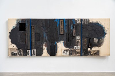 A mixed-media collage painting with black over an off-white canvas, the edges of white are visible. Various photographs and found objects are affixed to the canvas as are two blue bars that divide the painting in unequal thirds.