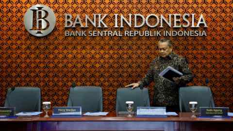 Perry Warjiyo, governor of Indonesia's central bank, stands holding documents at a conference table inside Bank Indonesia's headquarters in Jakarta