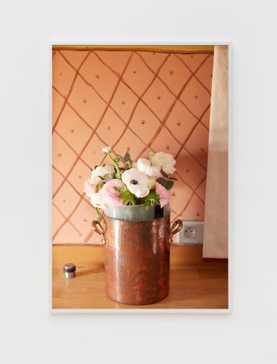 A photograph of a bouquet of white and pink roses in a copper bucket. 