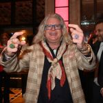 A man with long white hair smiling at the camera.