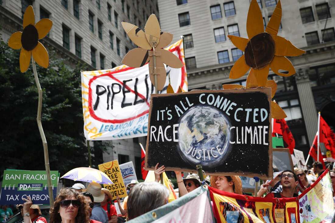 Climate change activists carry signs as they march during a protest in Philadelphia in 2016. Earlier that year, U.S. prosecutors allege hackers began targeting prominent American climate activists in an effort to gather information to foil lawsuits against the fossil fuel industry over damage communities have faced from global warming.