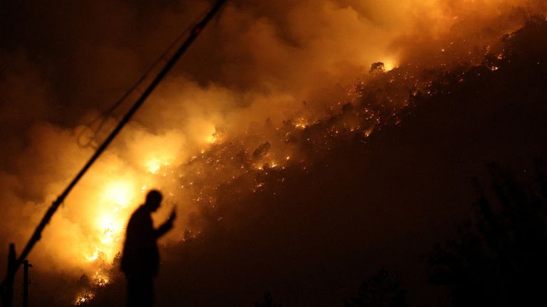 A member of emergency services stands next to a wildfire near Bulqiza, Albania, July 26, 2025. REUTERS/Florion Goga TPX IMAGES OF THE DAY
